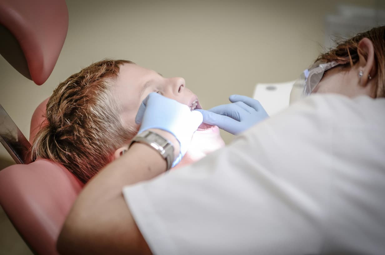 Tandlæge i gang med tandundersøgelse på dreng